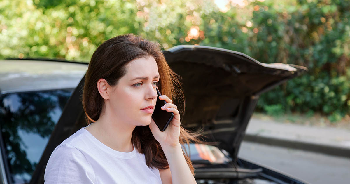 A woman seated in her parked car after a fender bender on a Lakewood Ranch road, one hand on her neck, the moment many auto accident injuries first show up and the Florida 14-day clock starts