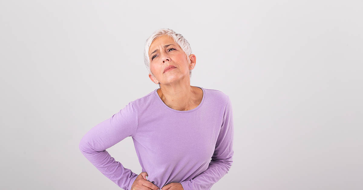 Older adult holding the outer side of their hip during a hip pain evaluation at Spine and Wellness Center Lakewood Ranch