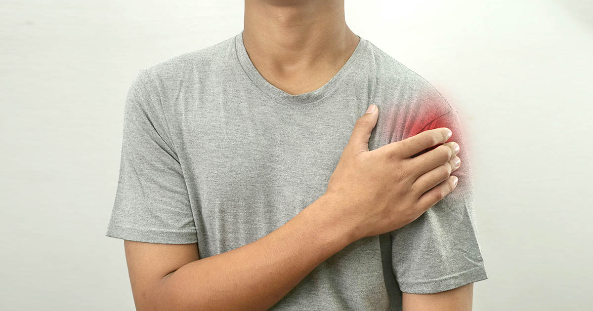 Person holding a sore shoulder while a Lakewood Ranch chiropractor examines the rotator cuff and range of motion