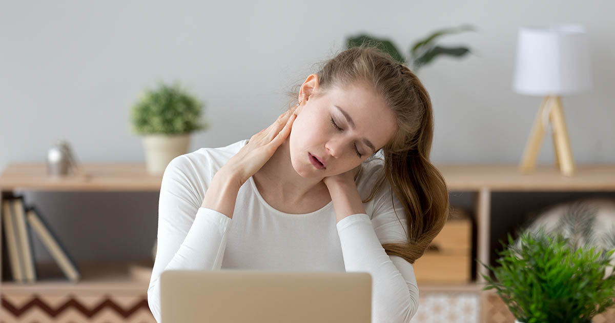Person rubbing a stiff, aching neck and shoulders from forward head posture before tech neck treatment at Spine and Wellness Center Lakewood Ranch